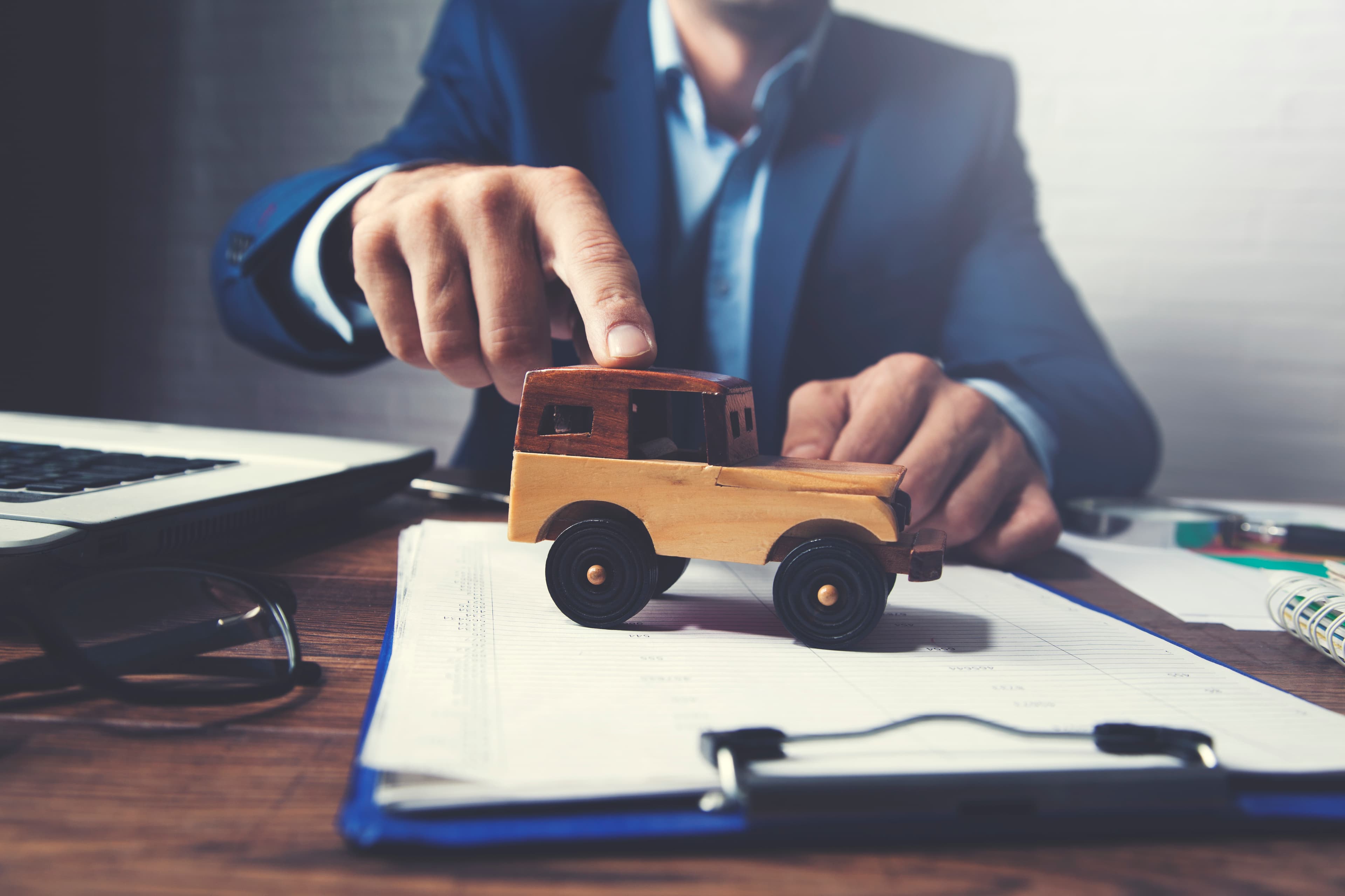 Person pushing toy car on documents, representing aggregate deductibles in transport insurance.