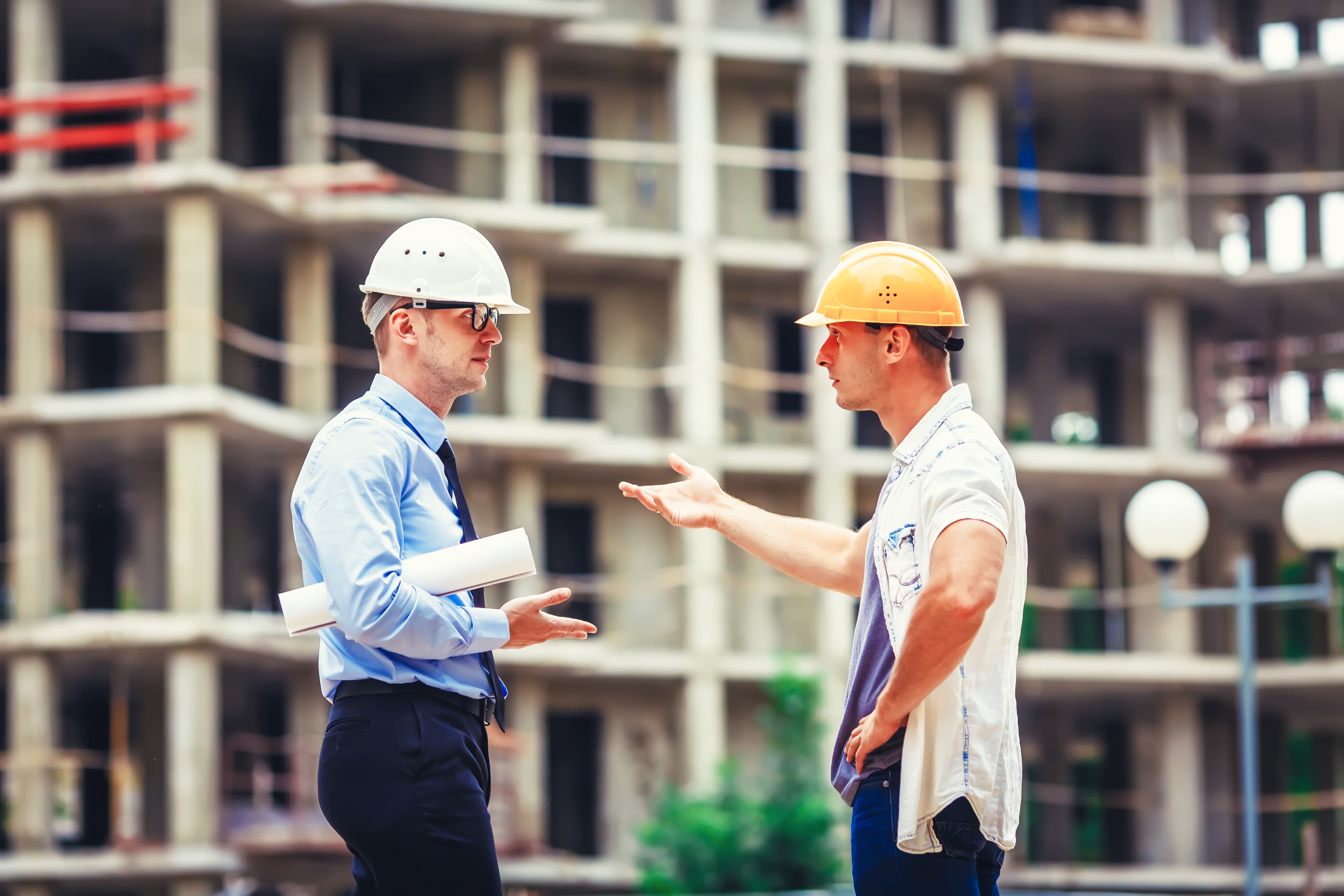 Two builders discussing construction all-risks insurance on a building site.